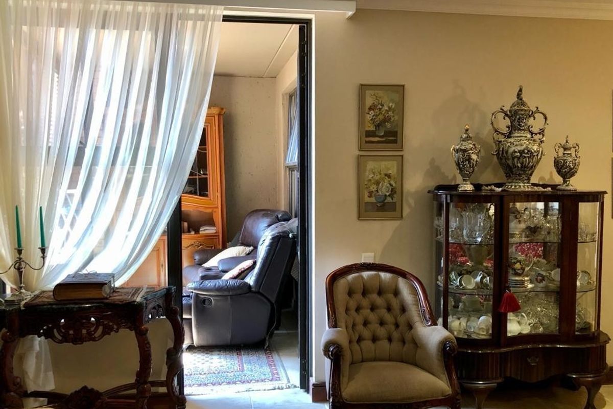 A living room area featuring tiled flooring and crown molding, with an open doorway leading to an adjacent room.