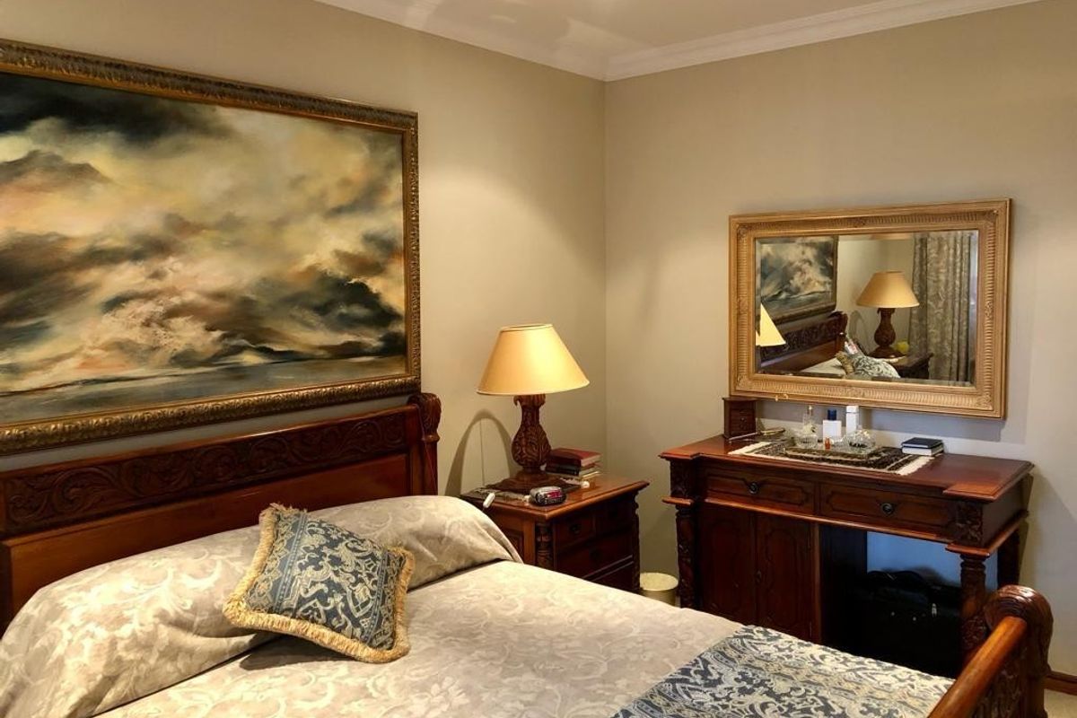 A well-maintained bedroom featuring neutral wall tones, recessed downlighting, and classic crown molding, providing a comfortable and inviting living space.