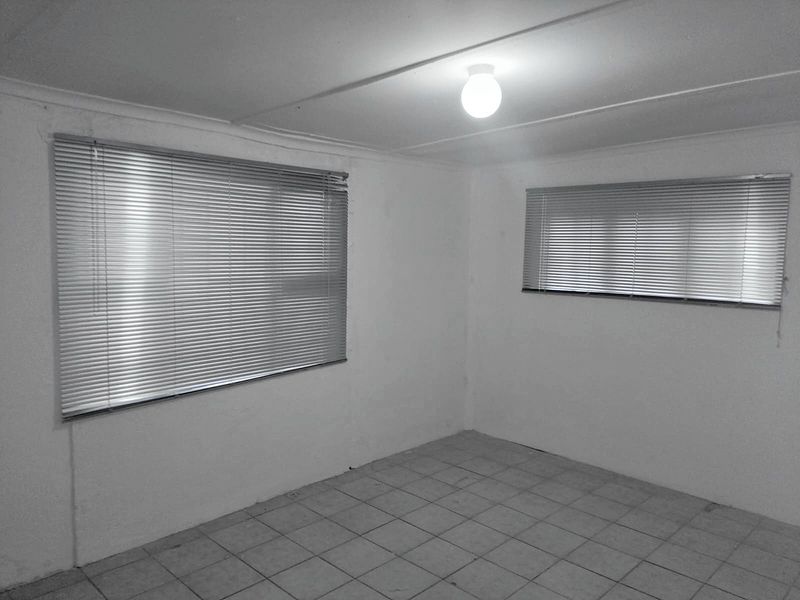 An empty bedroom featuring tiled flooring, venetian blinds, and a simple ceiling light fixture, offering a blank canvas for renovation.