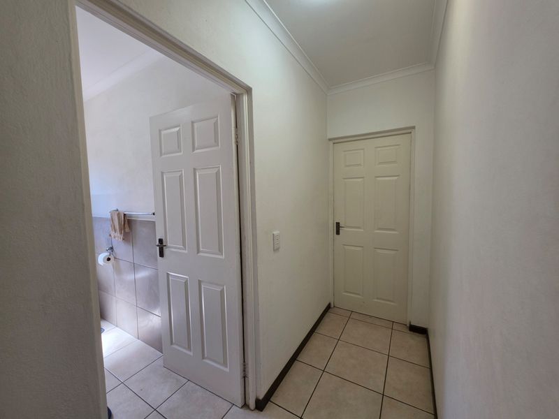 A clean and functional hallway featuring tiled flooring, neutral walls, and access to adjacent rooms through classic panelled doors.