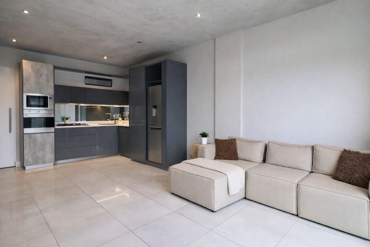 Modern open-plan living area featuring a sleek kitchen with integrated appliances, high-gloss cabinetry, mirrored splashback, and polished tiled flooring throughout.
