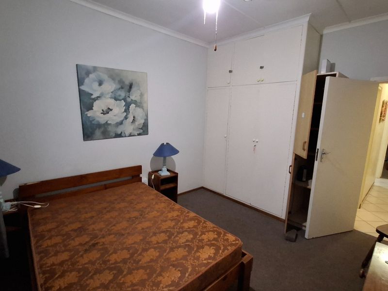 A bedroom featuring built-in cupboards and carpeted flooring, offering a functional space with potential for cosmetic updates.