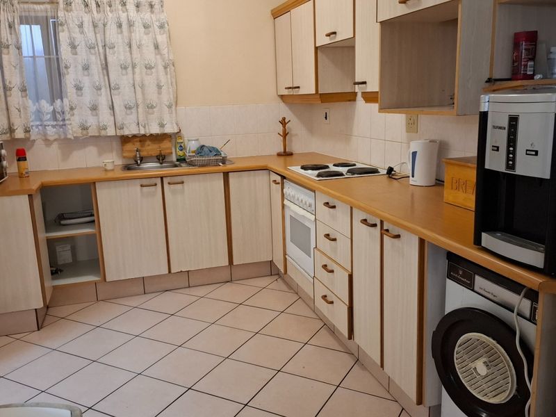 A functional kitchen featuring laminate cabinetry, tiled flooring, a built-in oven, and an electric hob, offering a practical layout for daily meal preparation.