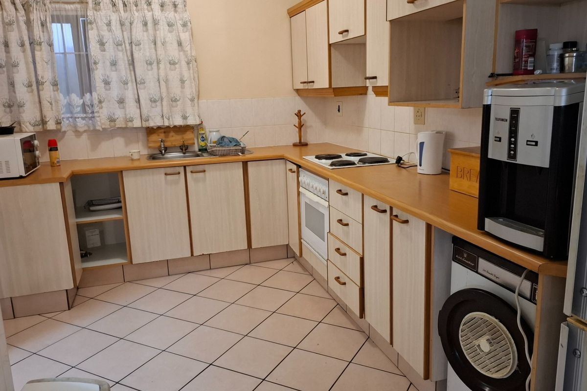 A functional kitchen featuring laminate cabinetry, tiled flooring, a built-in oven, and an electric hob, offering a practical layout for daily meal preparation.
