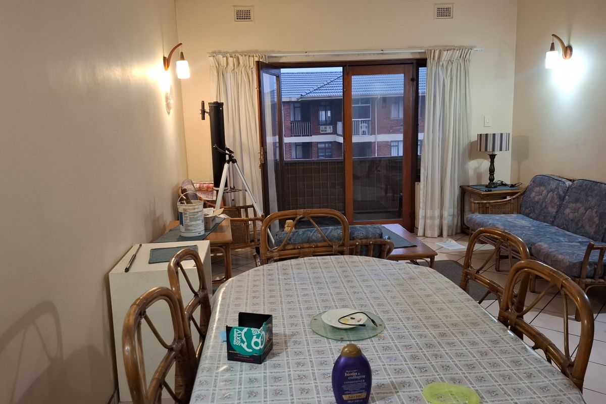 A living and dining area featuring tiled floors, wall-mounted lighting, and direct access to a balcony through sliding glass doors.