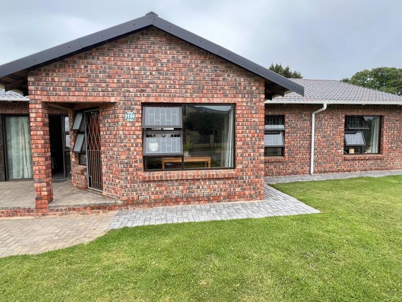 A well-maintained single-story face brick house featuring a tiled roof, aluminium window frames, and a neat paved walkway leading to the entrance.