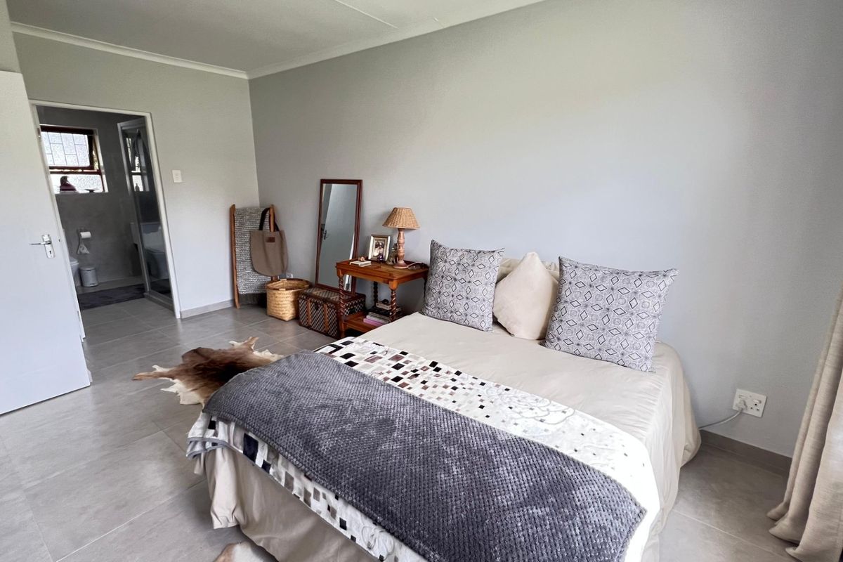 A well-maintained bedroom featuring neutral tiled flooring, cove cornicing, and direct access to an en-suite bathroom.
