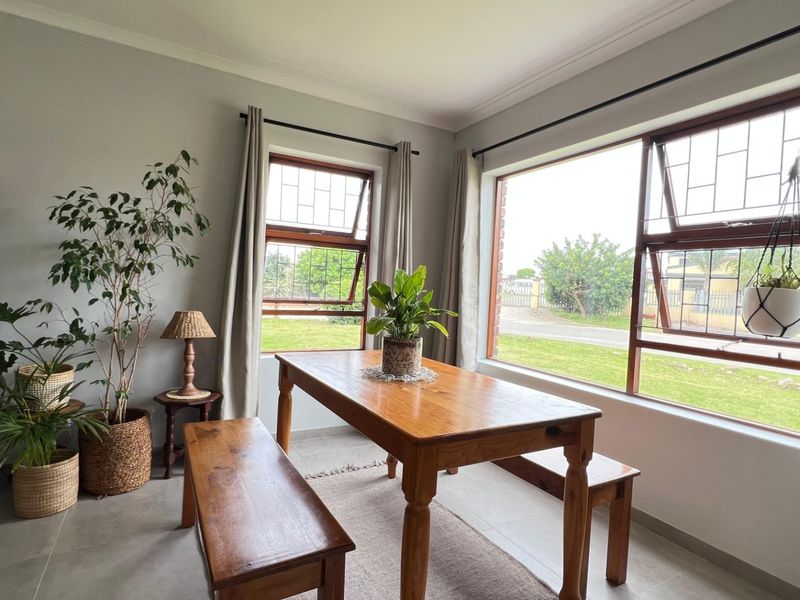 A bright living area featuring large windows with security bars, neutral wall tones, and tiled flooring, offering a comfortable and well-lit space.