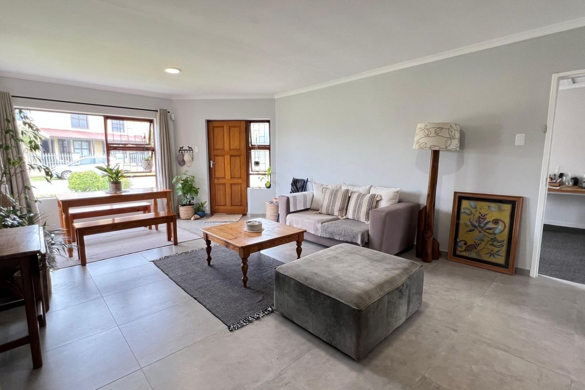 Spacious open-plan living area featuring neutral tiled flooring, recessed lighting, and a solid timber front entrance door.