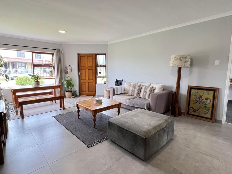 Spacious open-plan living area featuring neutral tiled flooring, recessed lighting, and a solid timber front entrance door.