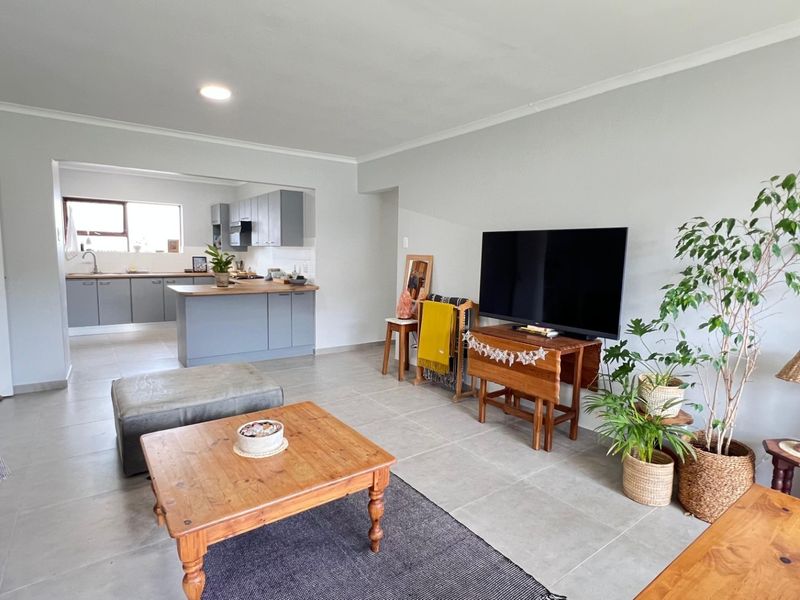 Spacious open-plan living area featuring modern grey kitchen cabinetry, a central island, and neutral tiled flooring throughout.