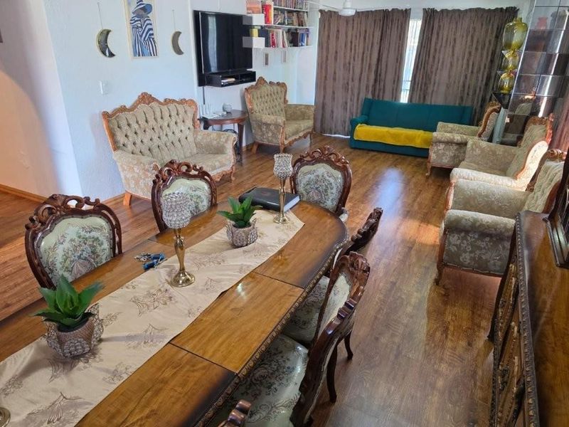 Spacious open-plan living and dining area featuring laminate flooring and built-in shelving, offering a versatile layout for family living and entertaining.