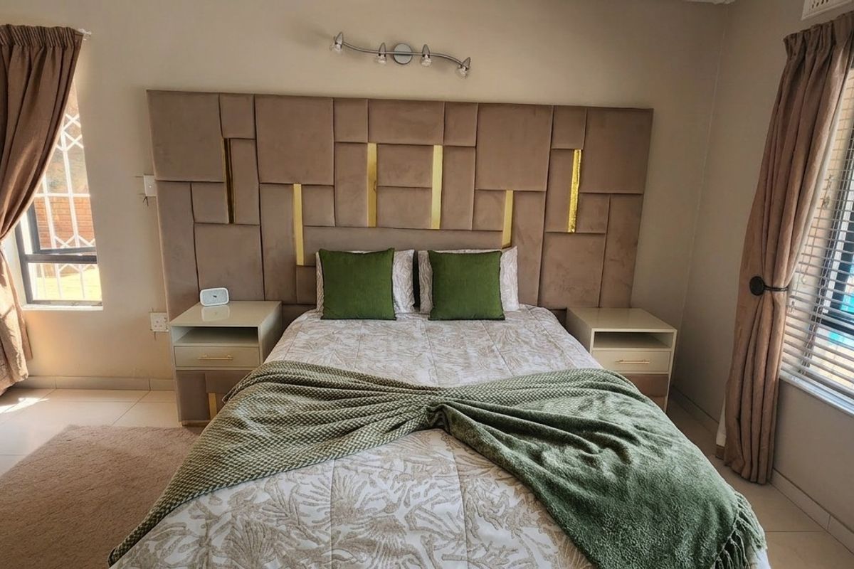 A well-maintained bedroom featuring tiled flooring, built-in cupboards, and a decorative upholstered headboard with integrated lighting.