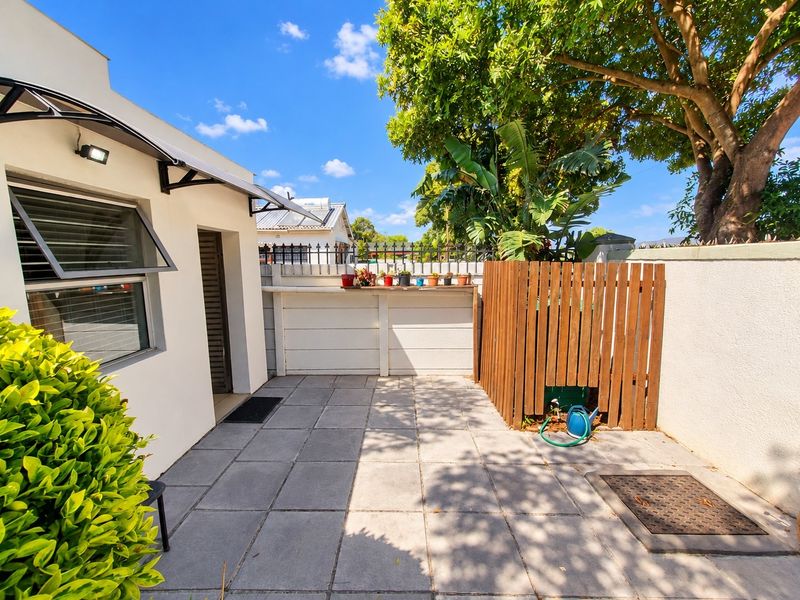 A neat, paved outdoor patio area featuring a timber privacy screen, external wall lighting, and an awning, providing a functional and private outdoor space.