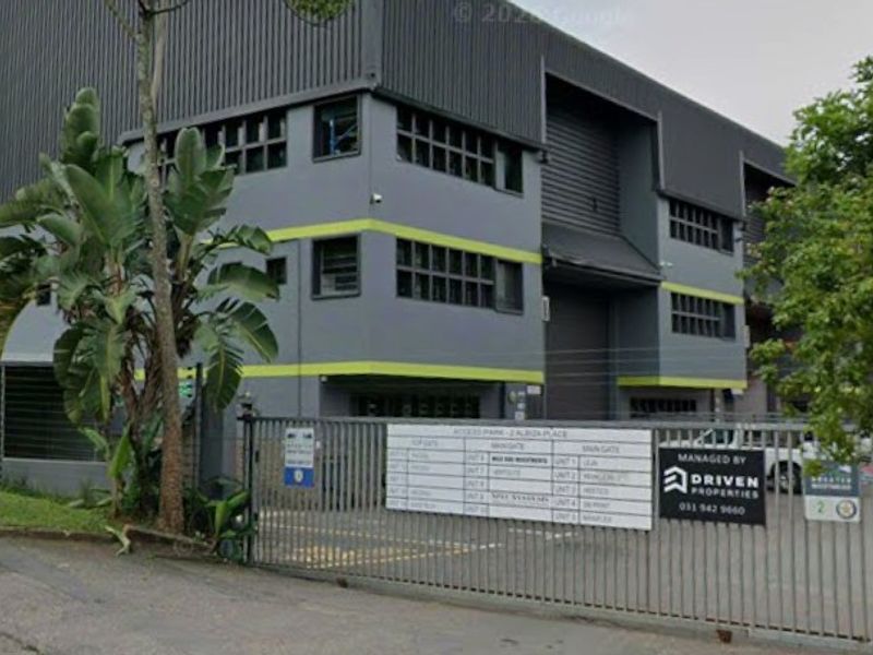 Front elevation of a multi-level industrial warehouse complex featuring metal cladding, roller shutter doors, and secure gated access.