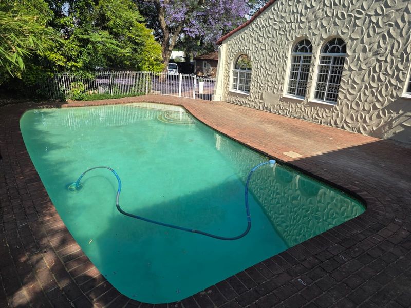 Outdoor pool area featuring brick paving, arched windows, and a textured exterior facade, providing a private space for relaxation and recreation.