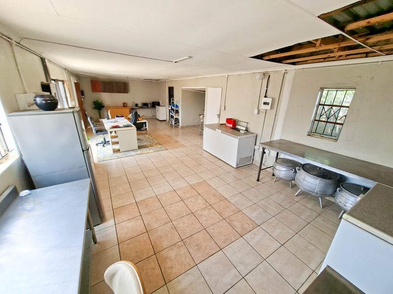 A large, multi-purpose utility space featuring tiled flooring and security bars, currently requiring ceiling repairs and general maintenance to improve its functionality.