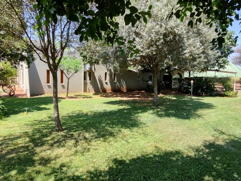 A view of the rear garden and lawn area featuring mature trees and established landscaping surrounding the property exterior.