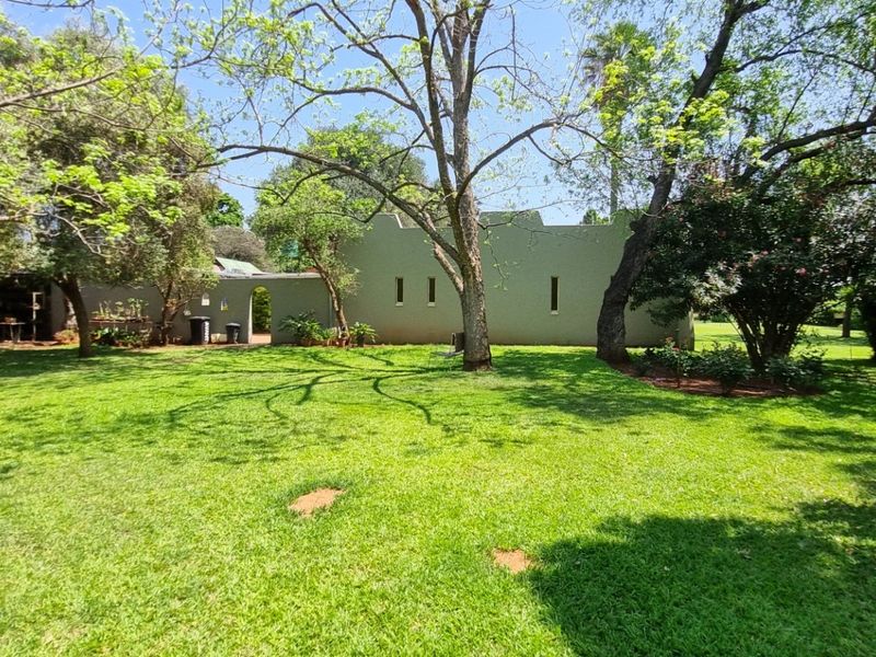 A spacious, well-maintained garden featuring mature trees and a large lawn area, providing a serene outdoor setting for the property.