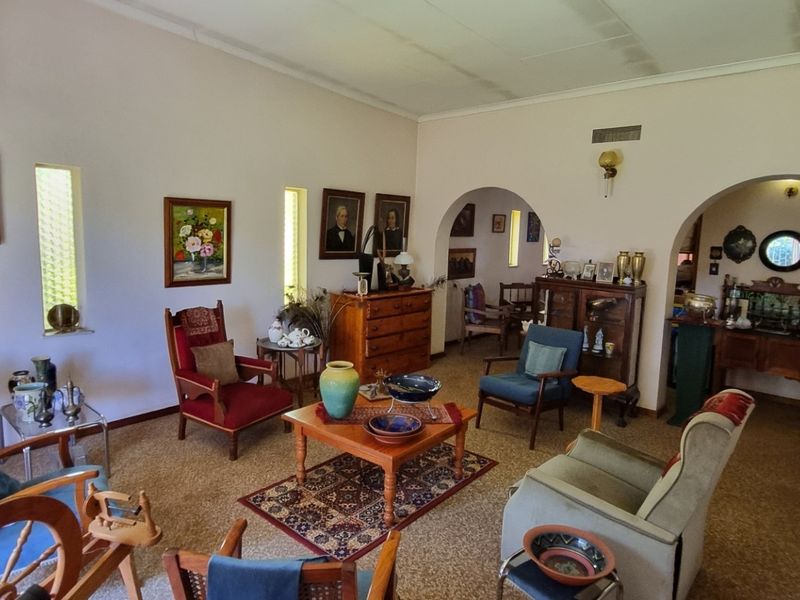 Spacious living room featuring classic arched doorways, vertical windows, and coved ceilings, offering a traditional layout with potential for modern updates.
