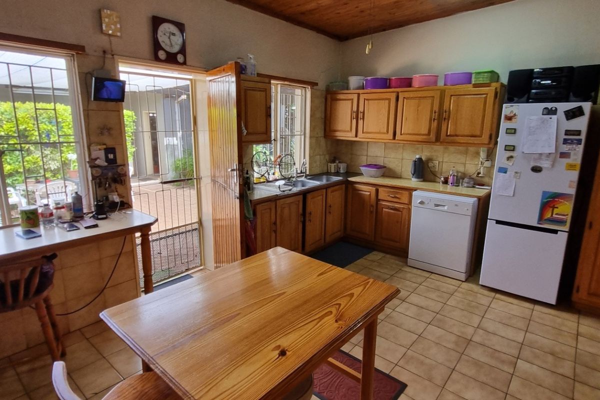 A functional kitchen featuring wooden cabinetry, tiled flooring, a double basin sink, and a built-in oven, with direct access to the outdoor patio area.