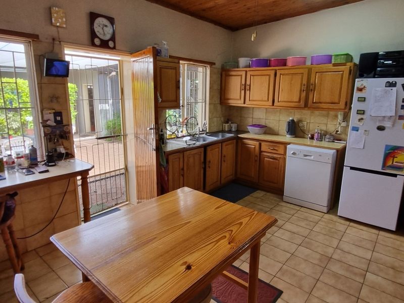 A functional kitchen featuring wooden cabinetry, tiled flooring, a double basin sink, and a built-in oven, with direct access to the outdoor patio area.