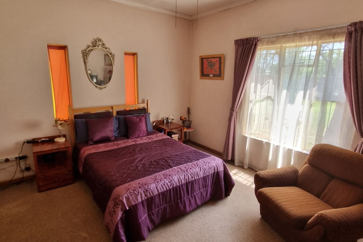 A spacious bedroom featuring carpeted flooring, vertical accent windows, and large windows with curtain rails, offering a comfortable and functional living space.