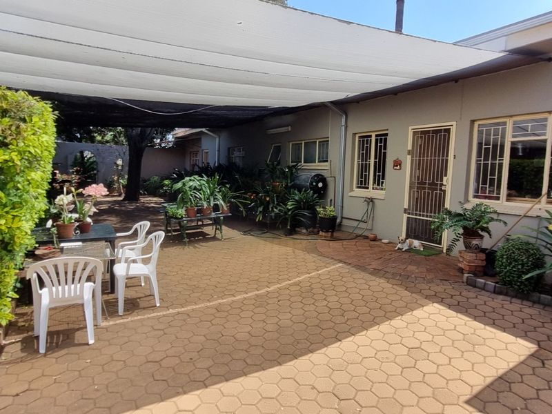 A paved outdoor patio area featuring a large overhead shade sail, providing a functional space for outdoor relaxation and entertainment.