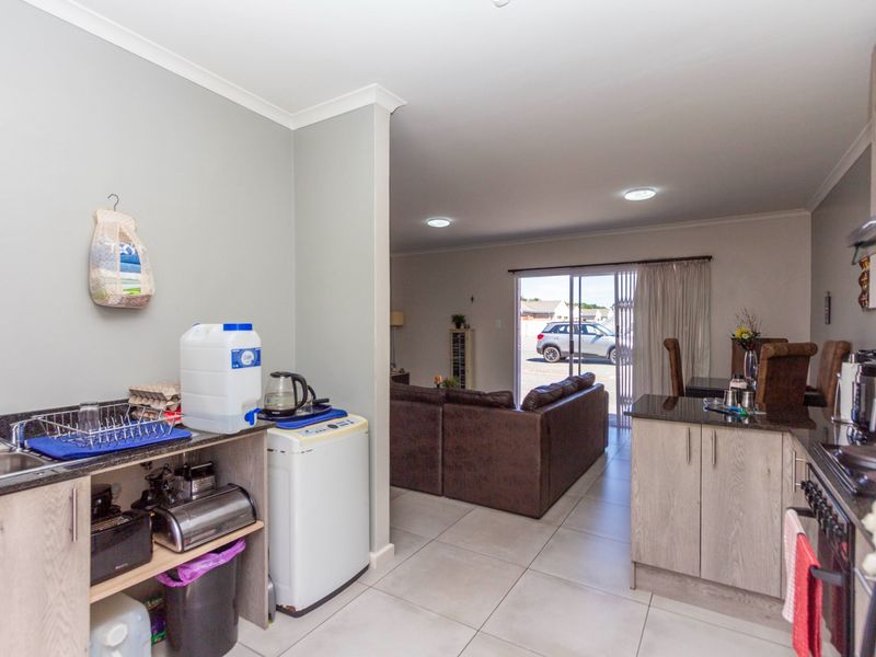 Open-plan kitchen and living area featuring tiled floors, granite countertops, and a sliding door leading to the exterior.