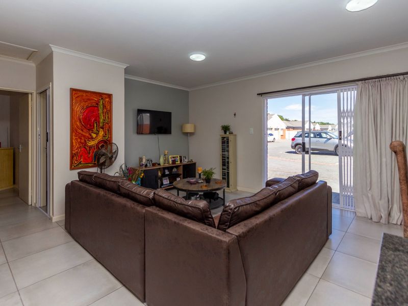 A bright living room featuring tiled flooring, recessed lighting, and a sliding glass door providing direct access to the exterior.