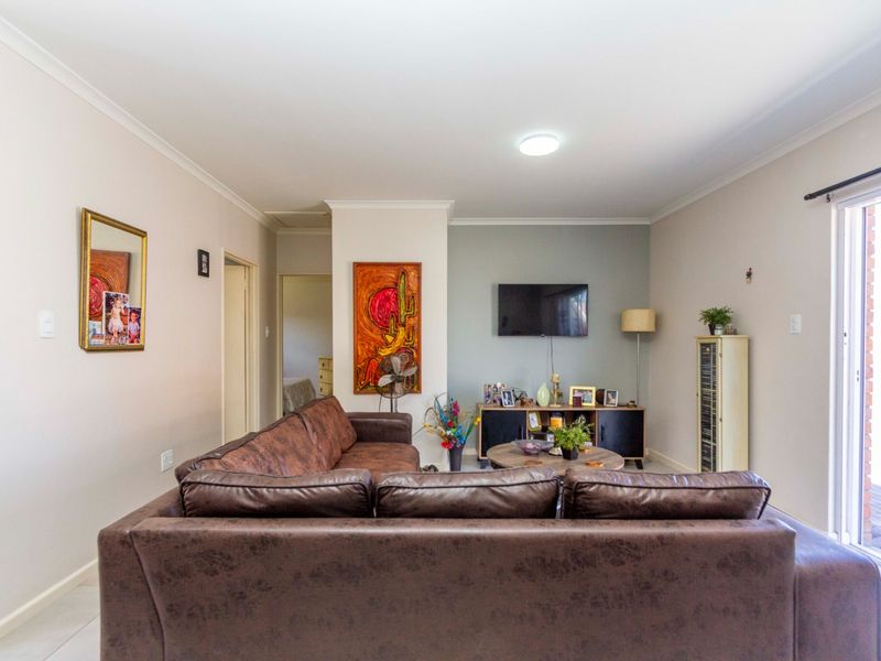A bright and spacious living room featuring tiled flooring, neutral walls, and a large sliding glass door providing access to the outdoor area.