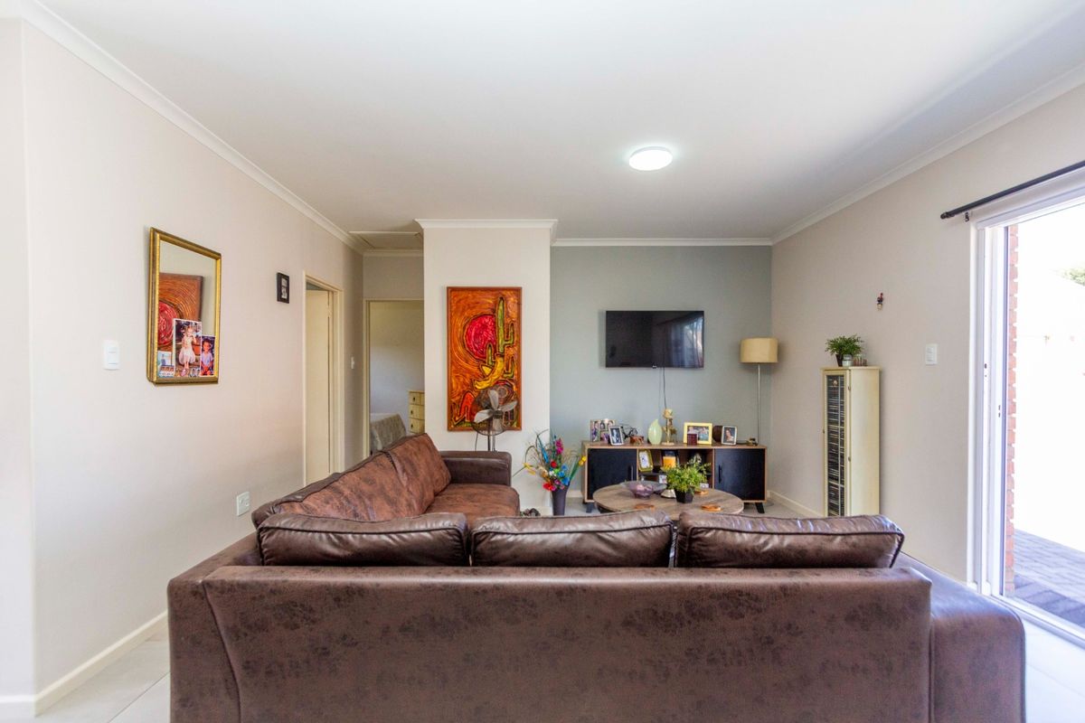 A bright and spacious living room featuring tiled flooring, neutral walls, and a large sliding glass door providing access to the outdoor area.