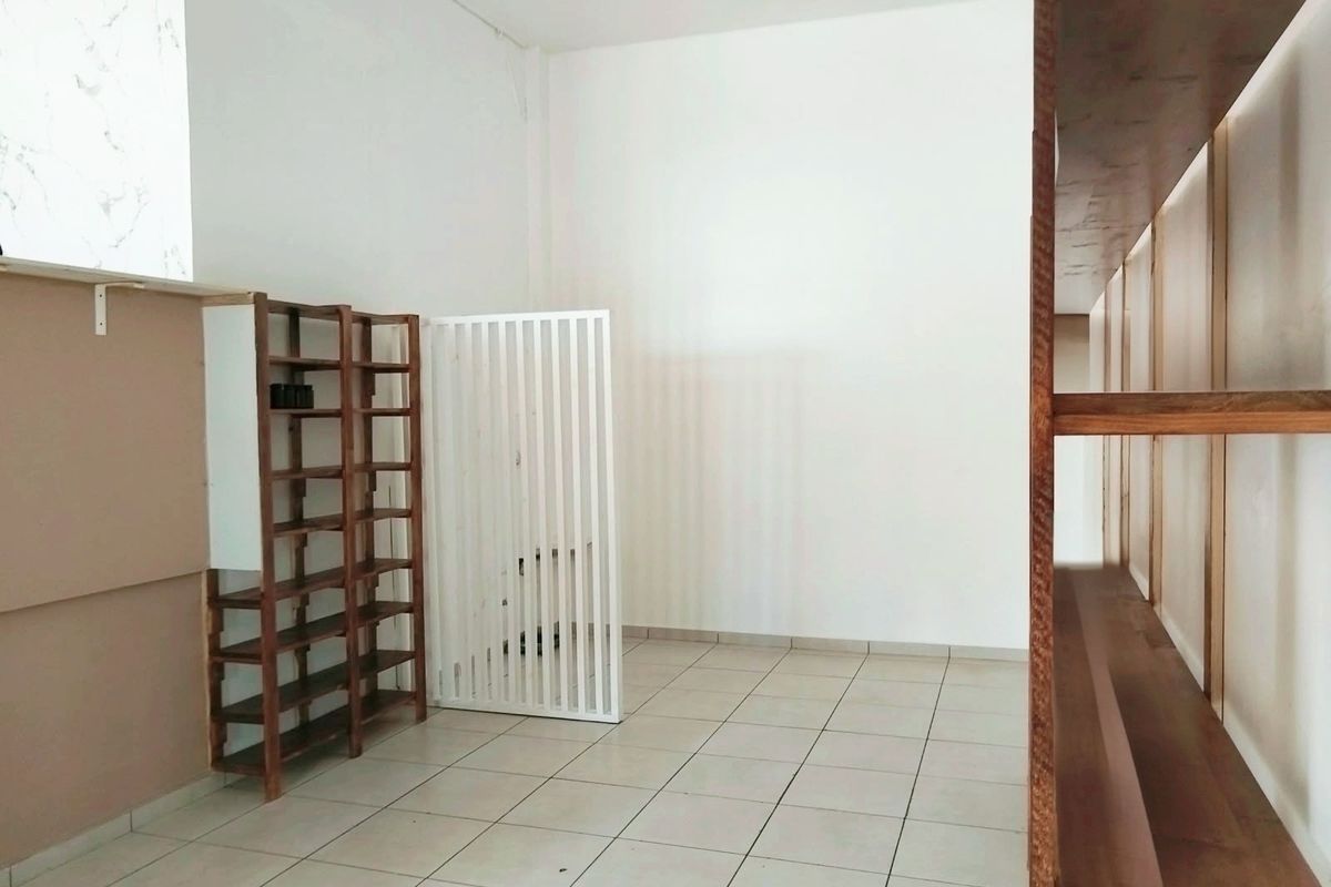 A clean, empty commercial utility space featuring tiled flooring, built-in wooden shelving units, and a decorative slatted room divider.