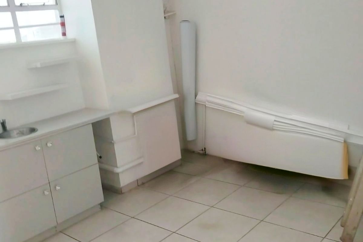 A small, empty kitchen area featuring built-in cabinetry, a sink, and tiled flooring, requiring some maintenance and cosmetic updates.