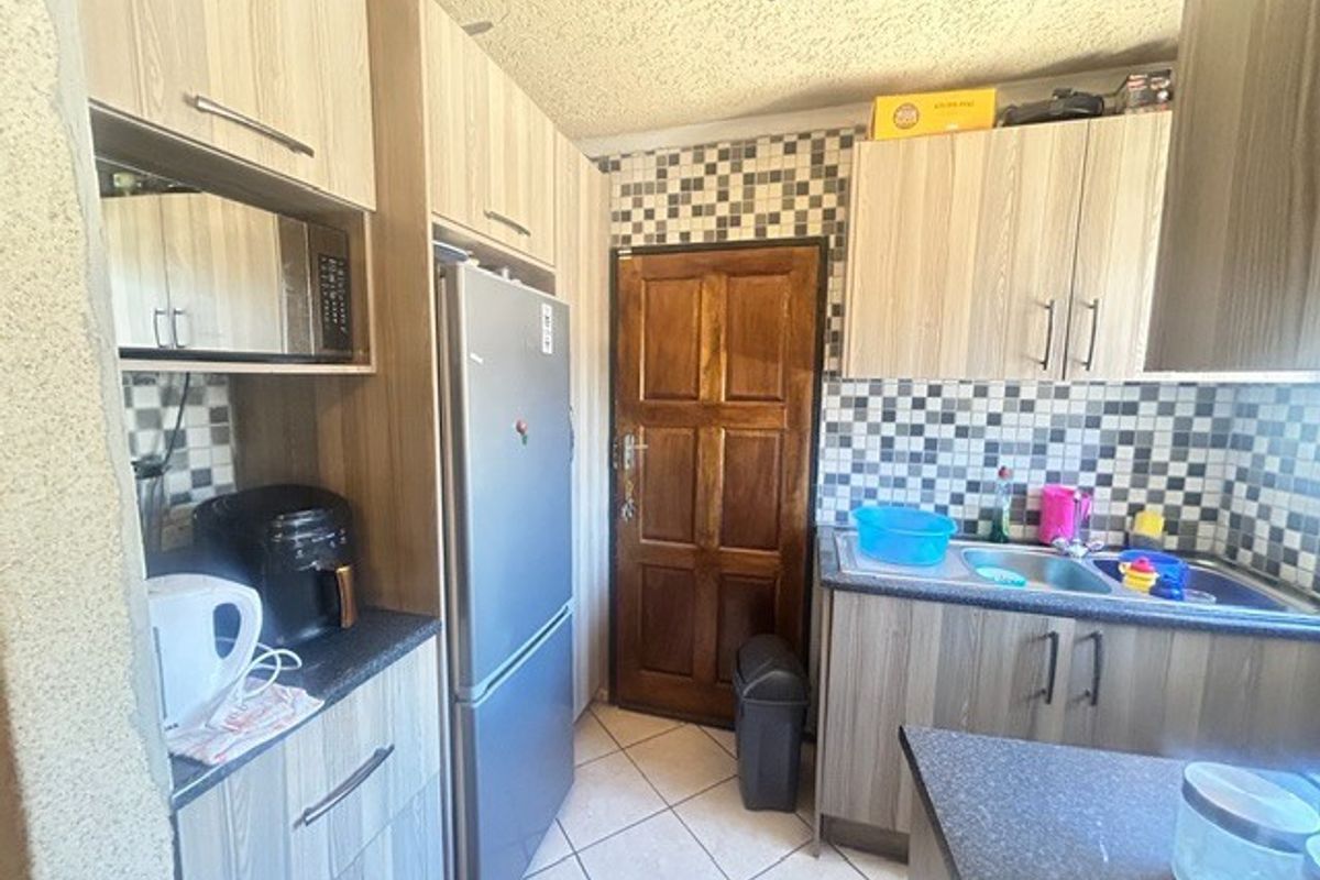 Compact kitchen featuring laminate cabinetry, mosaic tile backsplash, double bowl stainless steel sink, and ceramic floor tiles.