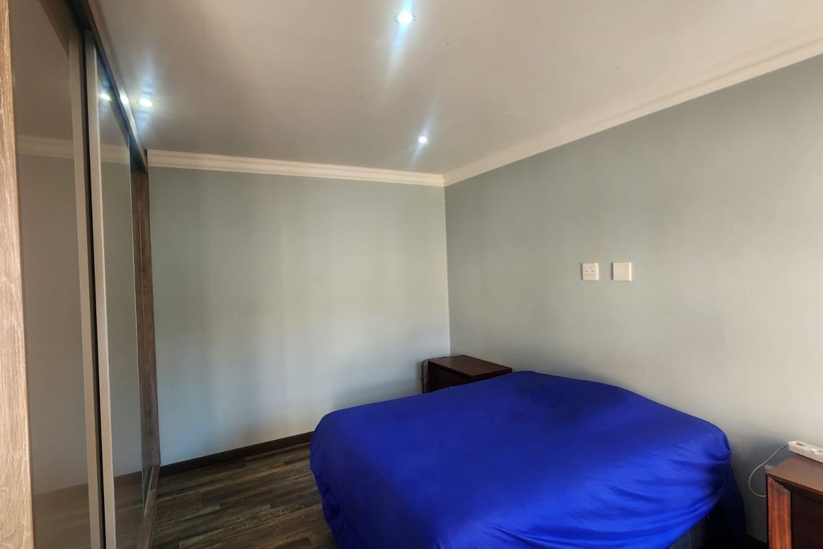 A bedroom featuring laminate flooring, recessed downlighting, decorative cove cornicing, and a large built-in sliding door wardrobe.