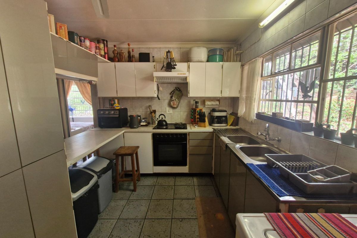 Functional kitchen featuring built-in cabinetry, a double sink, and a freestanding oven, with tiled finishes and natural light from the side window.