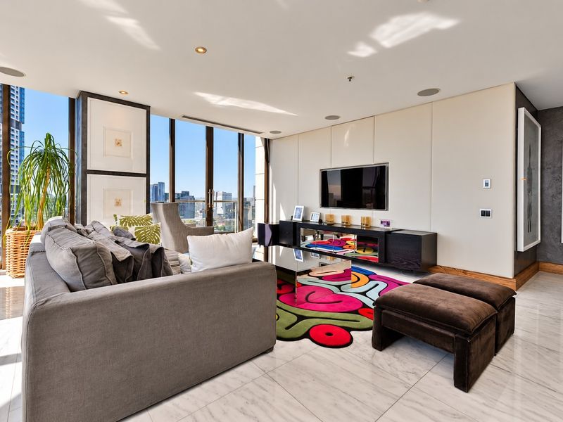 Modern living room featuring floor-to-ceiling windows with city views, marble flooring, and integrated ceiling speakers in a high-end apartment setting.