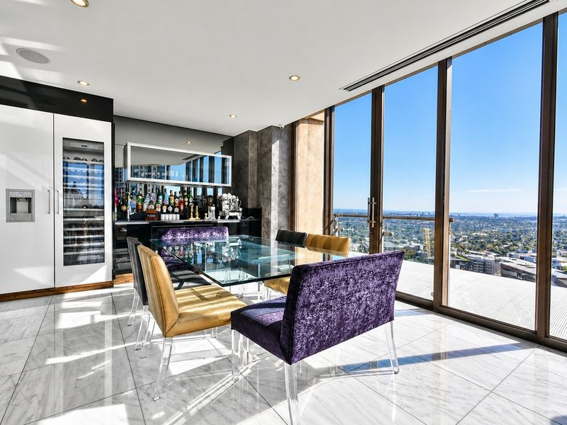 Modern open-plan living area featuring marble flooring, a built-in bar with wine storage, and expansive floor-to-ceiling windows offering panoramic city views.