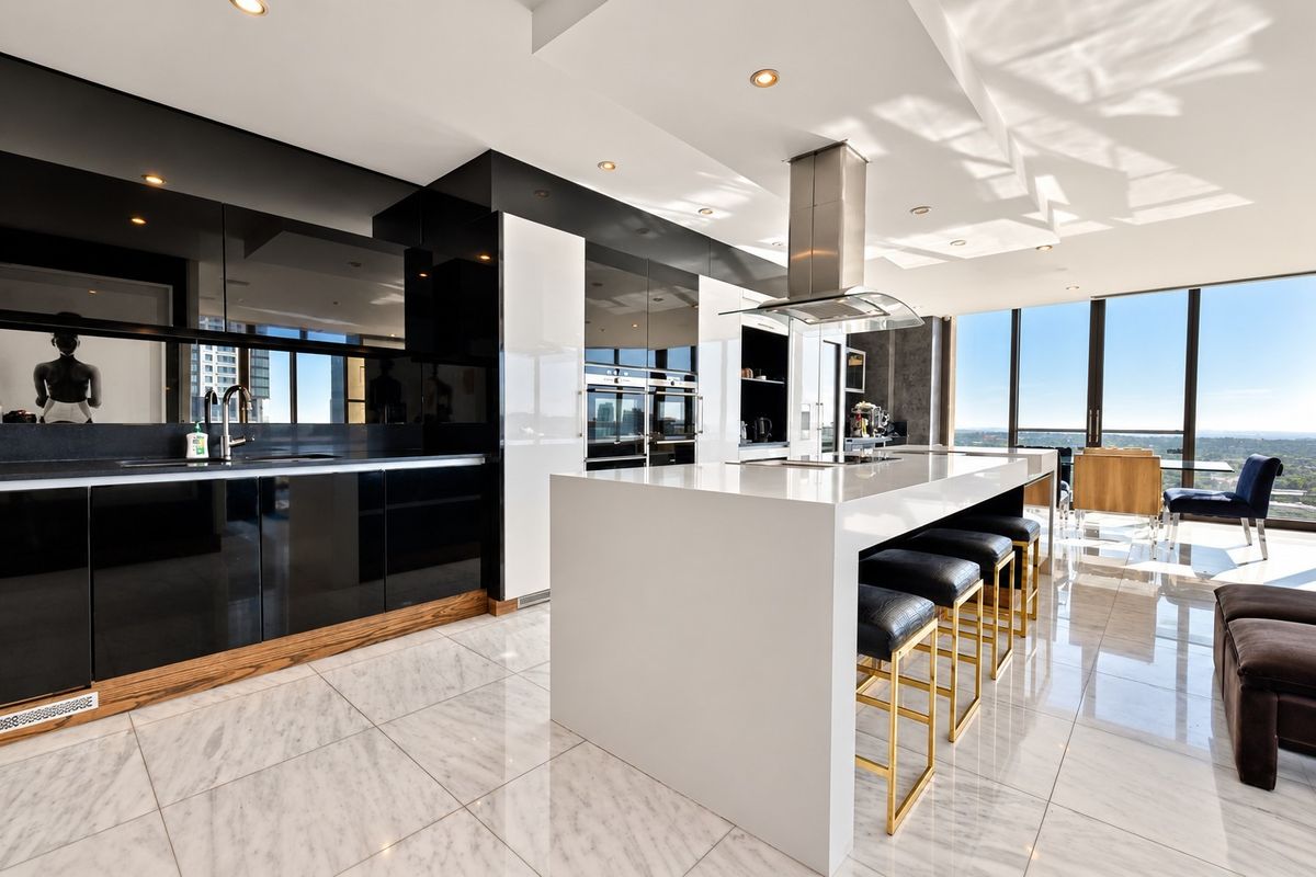 Modern high-end kitchen featuring a large central island, sleek high-gloss cabinetry, built-in appliances, and polished marble flooring with expansive city views.