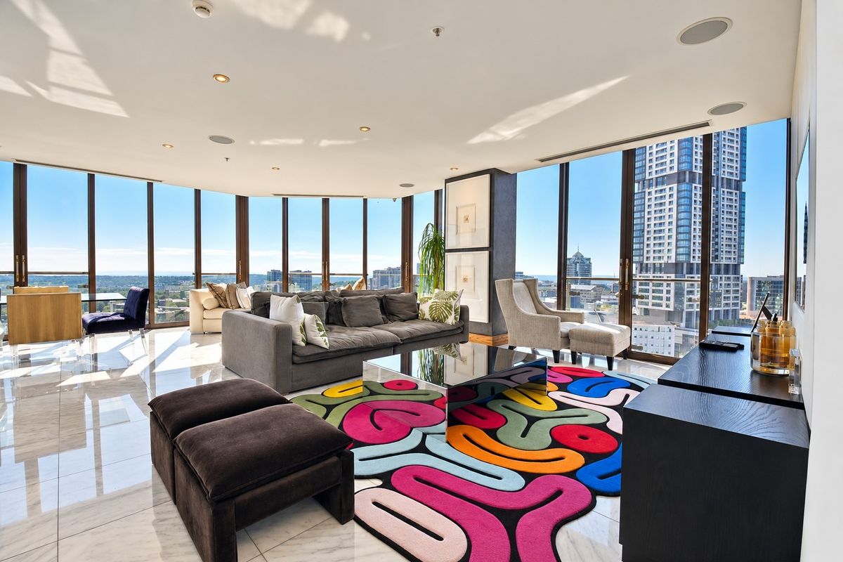 Spacious living area featuring floor-to-ceiling windows with panoramic city views, polished marble flooring, and modern recessed lighting.