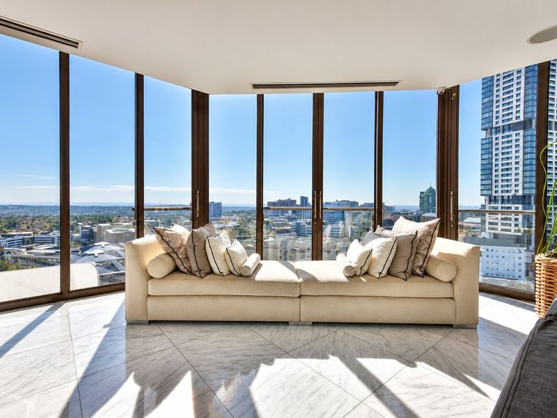 A bright, modern living area featuring expansive floor-to-ceiling windows with panoramic city views and elegant marble flooring.