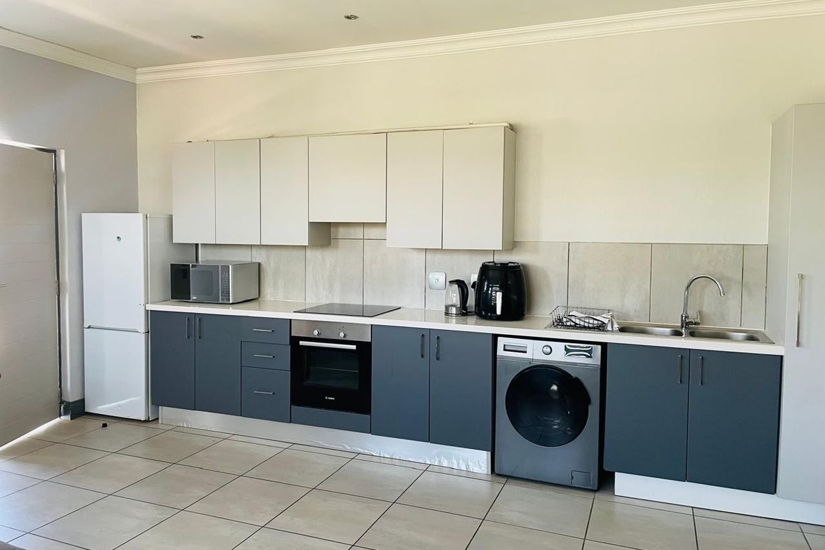 Modern kitchen featuring two-tone cabinetry, integrated oven and hob, tiled splashback, and tiled flooring in an open-plan layout.