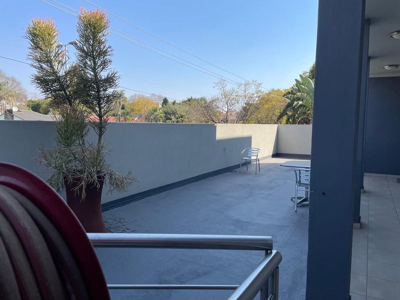 A spacious open-air balcony featuring a solid boundary wall, metal railing, and tiled flooring, offering an ideal space for outdoor relaxation.