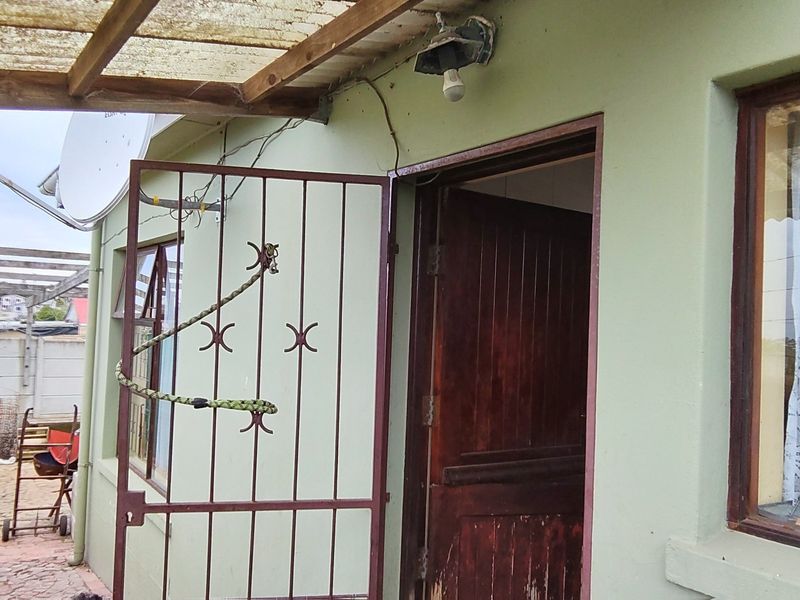 Covered patio area featuring a timber pergola, security gate, and wooden door, providing direct access to the exterior of the home.