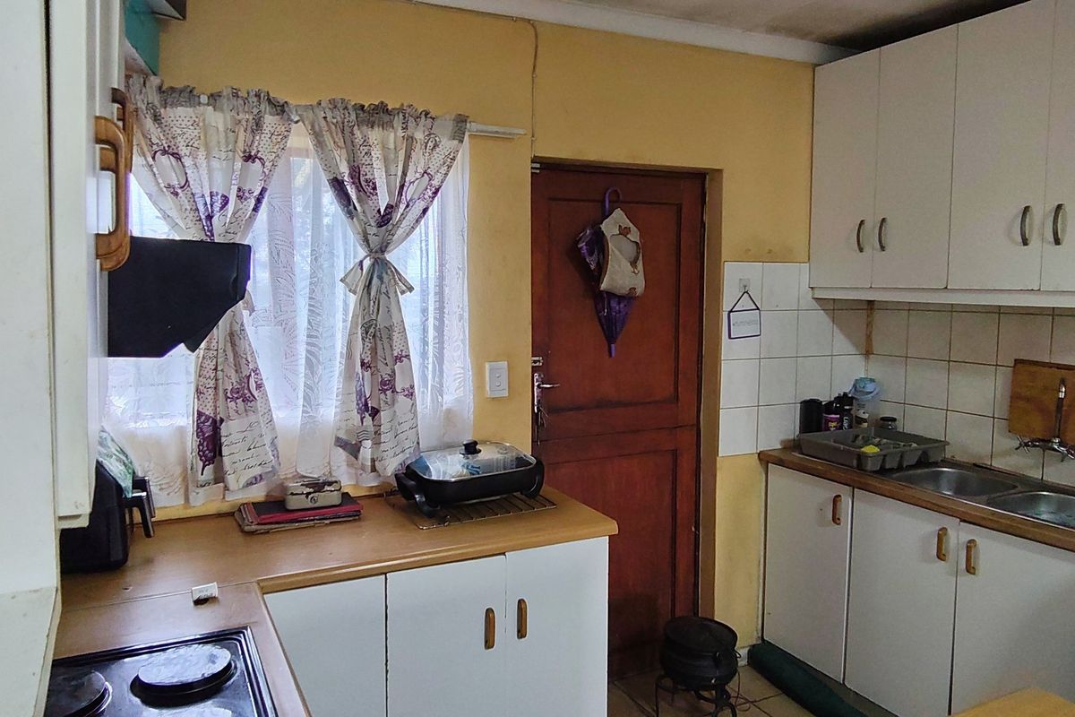 A dated kitchen featuring built-in cabinetry, laminate countertops, and a double bowl sink, offering significant potential for modernization and renovation.