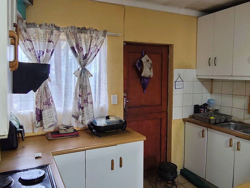 A dated kitchen featuring built-in cabinetry, laminate countertops, and a double bowl sink, offering significant potential for modernization and renovation.
