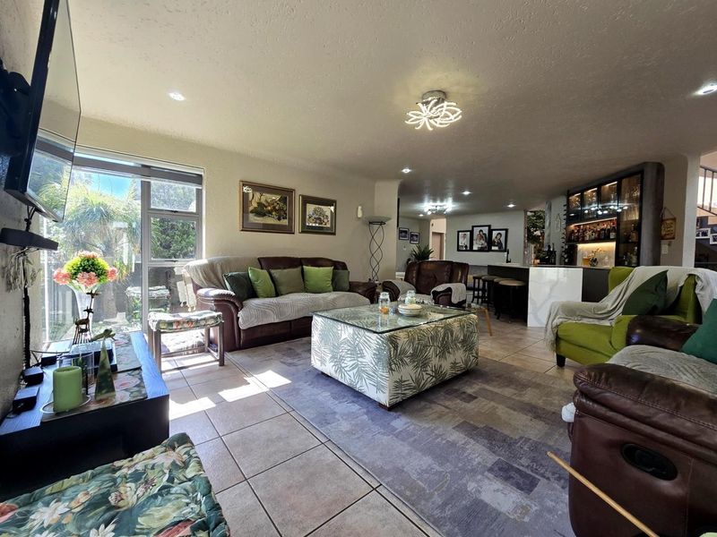 Spacious open-plan living area featuring tiled flooring, recessed lighting, and a built-in bar, creating a versatile space for relaxation and entertaining.