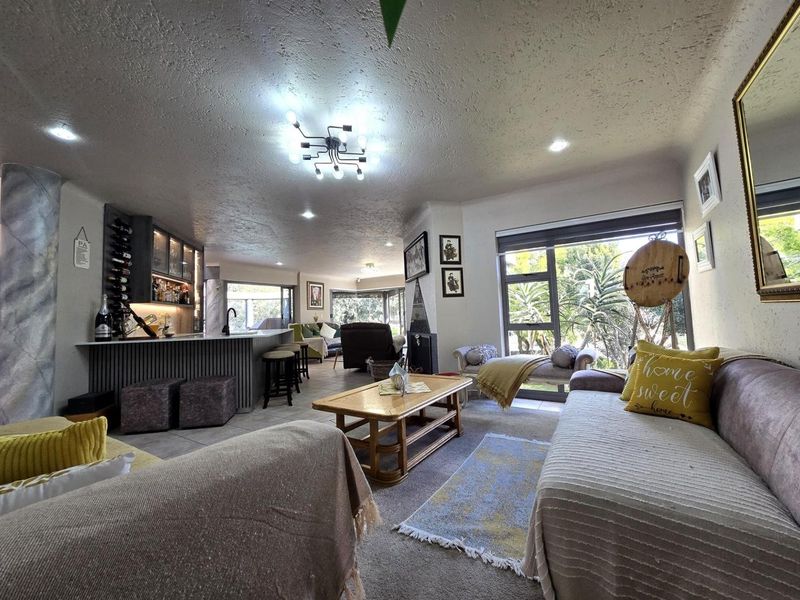 Spacious open-plan living area featuring a built-in bar, modern lighting, and large sliding doors that provide ample natural light and garden views.