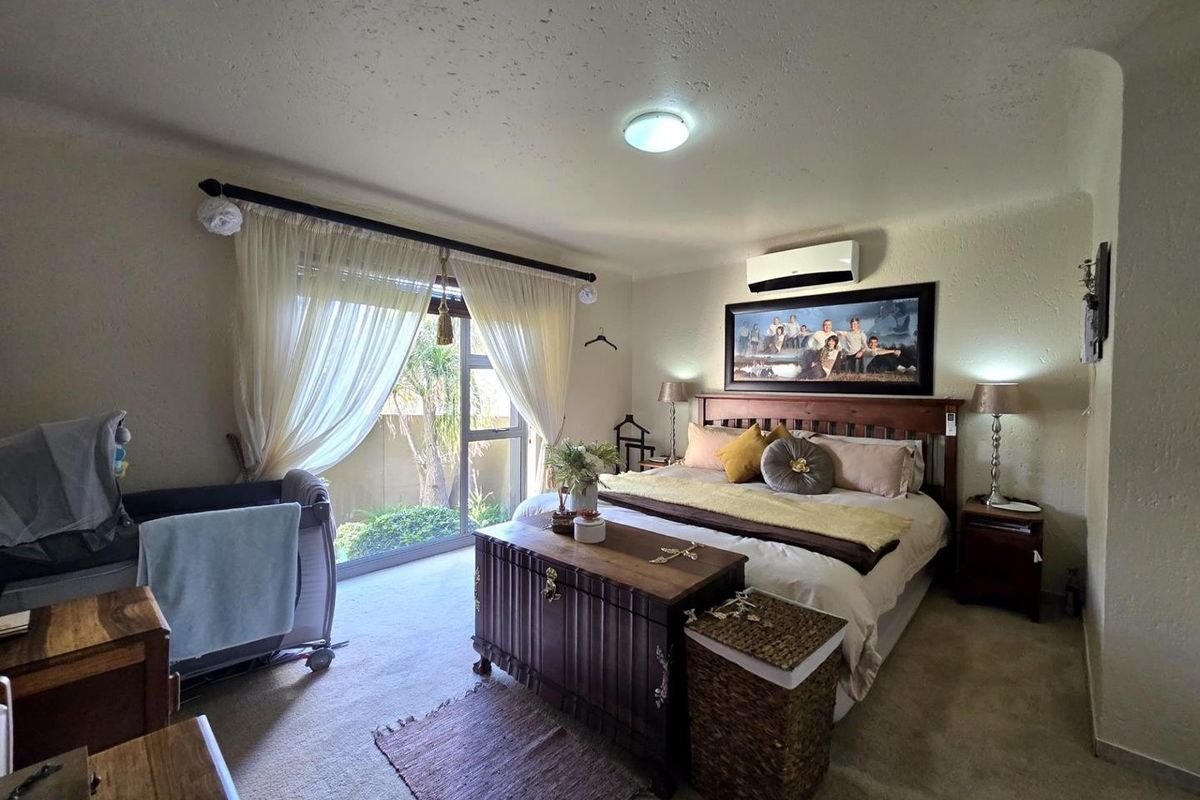 Spacious bedroom featuring carpeted flooring, a split-system air conditioner, and a large sliding glass door providing access to the outdoor area.